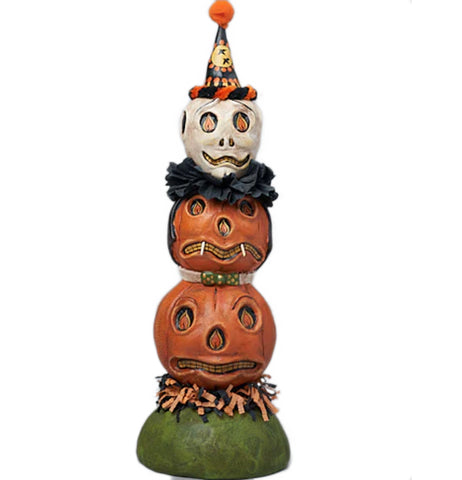 this is a pumpkin totem pole figurine with two orange pumpkins and a white pumpkin with a party hat. The base is green with a straw padding