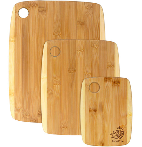Three wooden light brown/yellow cutting boards are stacked up against each other while magically standing up. They are all different sizes.