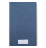 A blue journal has a white "property of" sticker" towards the bottom and in the upper middle of the cover indented into the front cover are Standard Issue Notebook No 17.