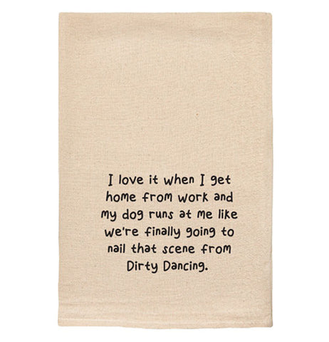 A beige tea towel with black text reading "I love it when I get home from work and my dog runs at me like we're finally going to nail that scene from Dirty Dancing."
