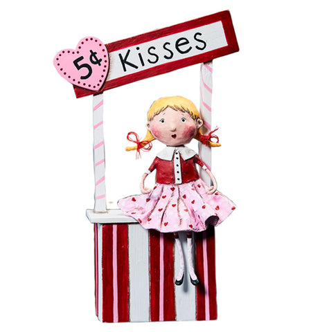 The 5 Cent Kisses shows the figurine of a girl wearing a pink skirt sitting on a kissing booth. A sign saying, "5 cent kisses" in black lettering is shown with the "5 cent" imprinted on a pink heart shaped sign.