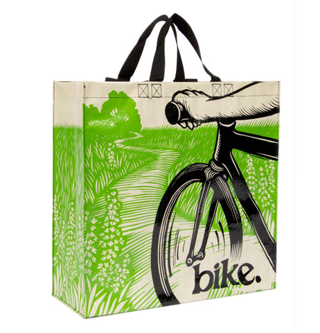 A path going through a green field and a partial view of the front of a black bike with someone's arm on the bike handle and the word 'bike' on the lower right also has short black handles for easy carrying.