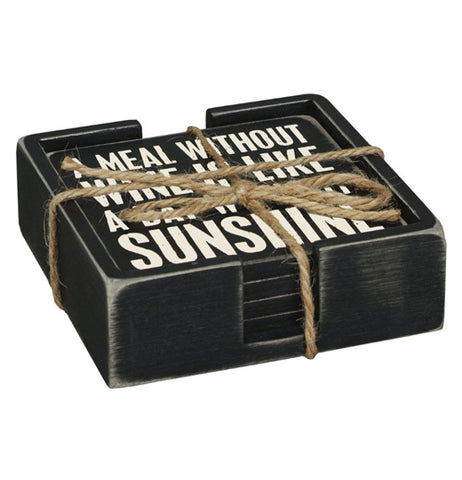 This black wooden holder contains a set of five black wooden coasters, the top of which reads in white lettering, "A Meal Without Wine is Like a Day Without Sunshine".