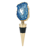 This golden bottle stopper features a blue gem with a hole in its middle at the top of the stopper.