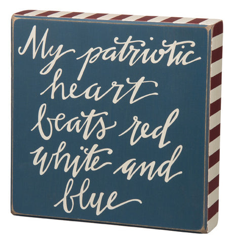 This box sign says "My Patriotic Heart Beats Red White And Blue." the sign is blue with red and white stripes around the edge and the words are white.