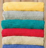 The teal towel is shown in the middle of a stack of towels.