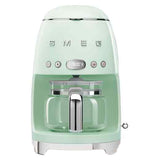 A pastel green coffee machine with a coffee carafe set up inside it. The base has small "feet" that elevate it slightly. The brand name "Smeg" and buttons are across the body.