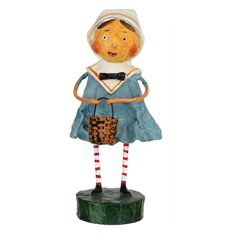 This figurine is of a girl wearing a blue dress and white hood is shown holding a brown wickerwork basket.