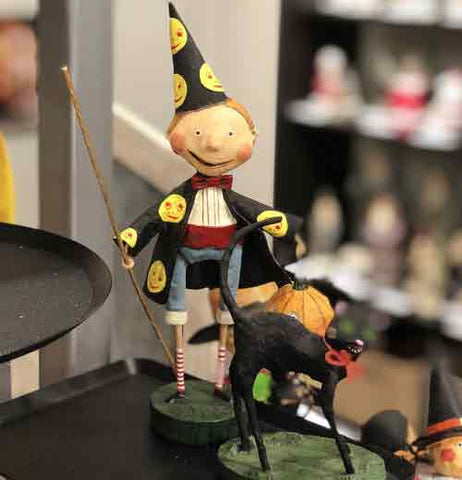 The sorcerer figurine is shown sitting on a shelf next to a black cat figurine.  