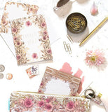 The Little "All For Love" Legal Pad sticks out of a purse with other pads  and gold stationary items on the table. 