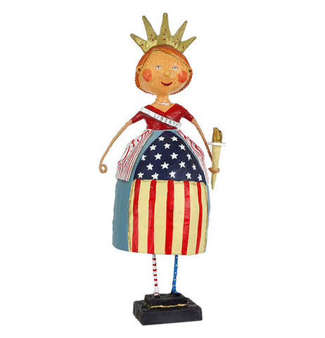 A smiling woman figurine wears a red, white, and blue, a crown, flaming on top of her head,  a torch on one hand, and  "liberty" on her side of the dress.