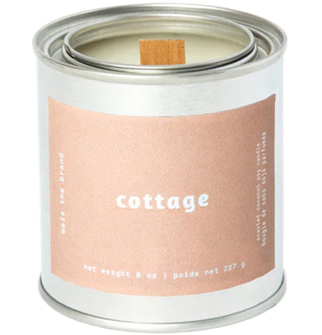 A gray tin candle-shaped can with a pastel brown label. The label says "Mala the brand--cottage--Net weight 8 oz. -- scented coconut soy candle." There is also French text, but this alt text writer is woefully monolingual.