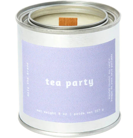A gray tin candle-shaped can with a pastel purple label. The label says "Mala the brand--tea party--Net weight 8 oz. -- scented coconut soy candle." There is also French text, but this alt text writer is woefully monolingual.