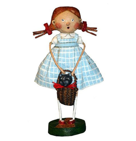 This figurine is of Dorothy holding her brown basket with Toto the little black dog inside it.  She is wearing her blue and white sleeveless dress.
