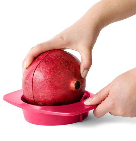 a close up of someone using the pomegranate tool to slice a red pomegranate