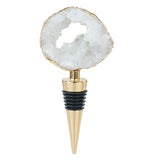 This golden bottle stopper features a white gem with a hole in its middle at the top of the stopper.