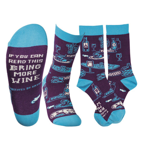 These are purple socks with light blue toes, tops, and heels with wine, cheese, and food imagery and white writing on the bottom that says "If You Can Read This Bring More Wine" over the purple background.