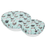 A pastel blue bowl cover with gray, black, and/or white cat heads all over it.