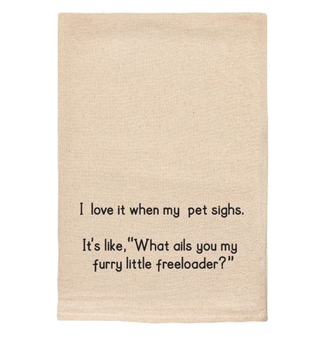 A beige tea towel with black text reading "I love it when my pet sighs. It's like 'What ails you my furry little freeloader?'"