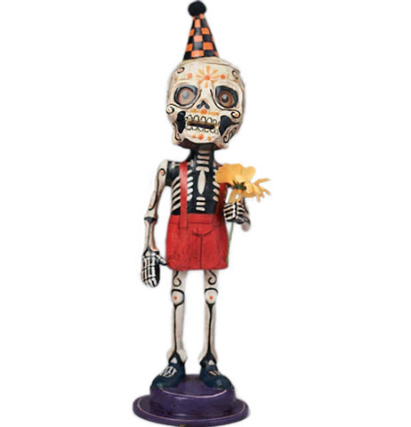 Maeto is a figurine wearing a sugar skull mask and black and orange party hat and wearing red short suspenders