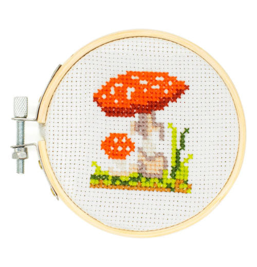 Embroidered picture of a mushroom on a small hoop held together by a bolt.