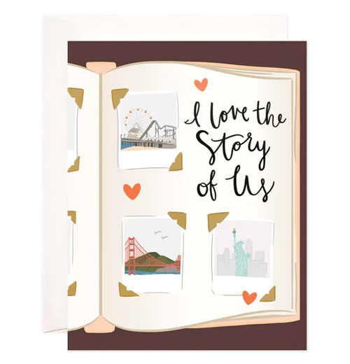 A card with an auburn brown colored background and a cut off open book printed on it that is open with pictures of different places like the statue of liberty, the golden gate bridge, and a ferris wheel with the words I love the story of us.