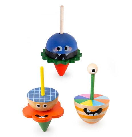 Three little monster spinning tops. One blue with a white stem, green middle and red tip, second is like a tan with yellow stem, blue with stripes in it with orange middle and green tip, the third is a color wheel on top with a green stem with an eyeball on top, striped tan and orange going down to the tip horizontally.