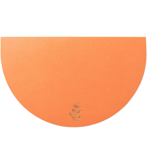 An orange, half-circular notepad has a mushroom design in the center bottom of it.