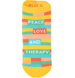 Yellow sock with different colored squares stacked up like bricks on the middle part and the words "Peace, Love and Therapy". the colors of the blocks are pink, blue, red, yellow and turquoise.