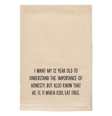 A beige tea towel with black text reading "I want my 12 year old to understand the importance of honesty. But also know he is 11 when kids eat free."