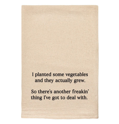 A beige tea towel with black text reading "I planted some vegetables and they actually grew. So there&