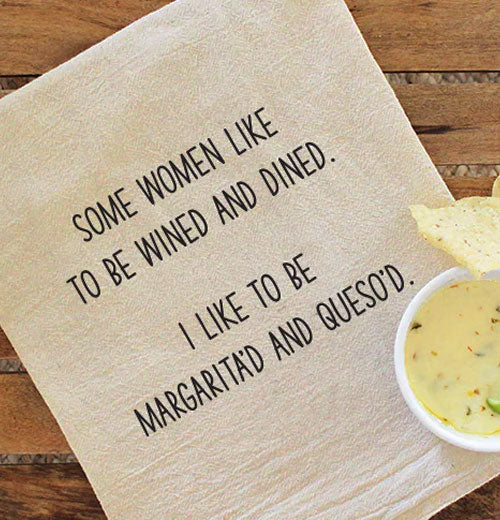 A beige dish towel with black text reading "Some women like to be wined and dined. I like to be margarita&