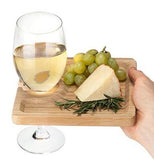 Some grapes and cheese are shown sitting on the wooden board. A wine glass is shown attached to the slot shape in the board.