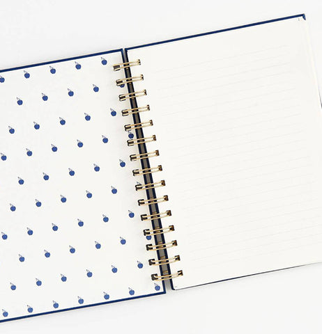 The opened Spiral "No. 1 Teacher" Notebook has designs of blue apples on the left, and lined paper on the right. 