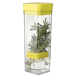 The container is shown closed up with the herbs being held in the holder below the middle. Underneath the holder is a melting ice cube. Above the holder are the stems of the green herbs.