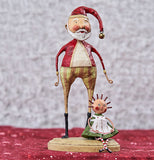 This jolly old santa from up close with a santa hat with a red and white shirt with green and red striped pants with a dolly beside him.