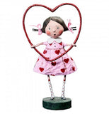 The Framed with Love figurine shows a girl with a pink dress with red hearts holding a red heart hula hoop. 