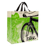 A path going through a green field and a partial view of the front of a black bike with someone's arm on the bike handle and the word 'bike' on the lower right also has short black handles for easy carrying.