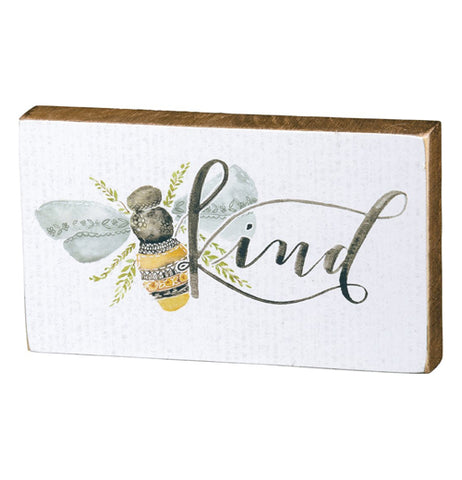 This white box sign features a design of a honey bee next to some black text that reads, "Kind".