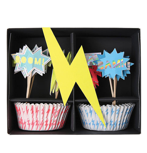The black package of the "Super Hero" Cupcake Kit has a yellow lightning bolt and shows cupcake wrappers and the toppers. 