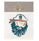 This front view of a stack of temporary tattoos shows a pirate face with a thick black beard, a golden eyepatch, and a red-orange bandanna under a hat with the skull and crossbones logo on it. In gold lettering at the cardboard top of the packaging are the words, "Meri Meri Tattoos".