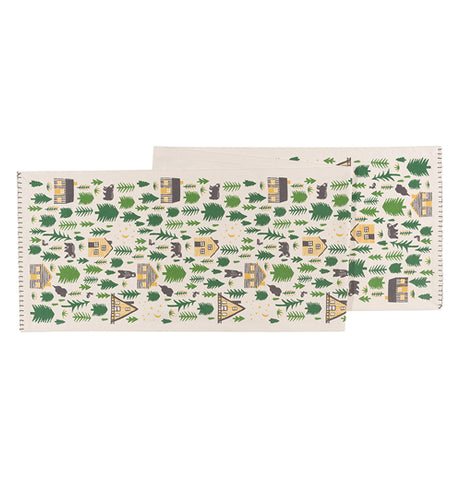 This white table runner features a unique design of brown cabins and black bears in the middle of a forest.
