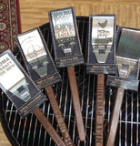 The spatula with the words all over its metal head is shown mixed in with other metal spatulas with different designs on their heads.