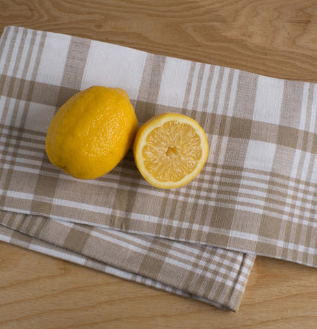 A brown and white plaid Jumbo Dish towel that is laying on a table with lemons on top.