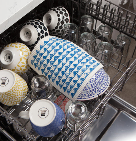 A dishcloth resting on a bunch of dishes within a dishwasher. 