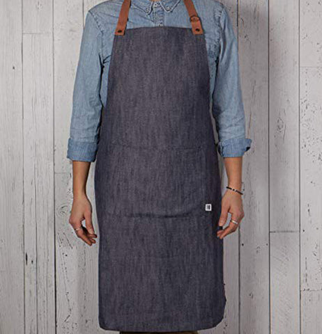 Someone wearing the Denim renew apron that has the adjustable leather neck strap.