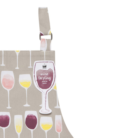 Close up of the corner of the "Wine Tasting" Apron and shows several different wine glasses on a gray background and a tag shaped like a wine glass attached to the adjustable strap.