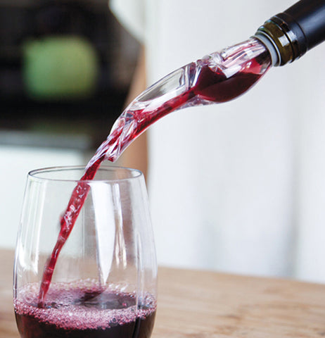 Some wine is shown pouring from a bottle topped with the plastic stopper.