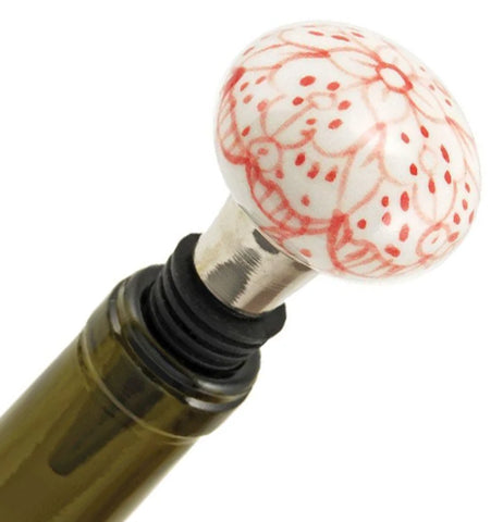 Showing wine bottle stopper with painted floral design plugged in a wine bottle.