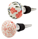 Country styled wine bottle stoppers with floral designs painted on ceramic top pointed vertically upwards.